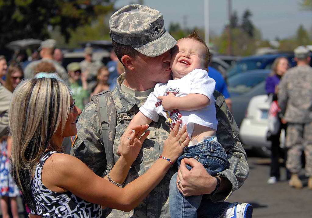 A soldier holding his child beside his family